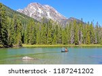 Grand Teton National Park, Wyoming. Beautiful mountain scenery, Jenny lake surrounded by pine tree forest, family in the kayak on the lake.