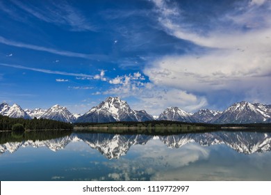 The Grand Tetons in Wyoming are reflected in the still waters of Jackson Lake.  This is a popular vacation destination in the Yellowstone and Jackson Hole areas.