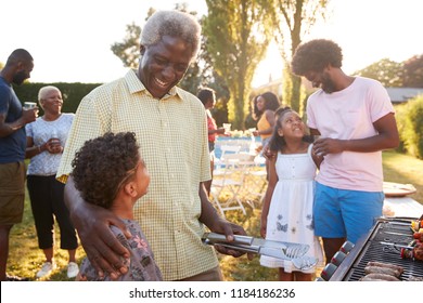 Grandad And Dad Talking With Kids At A Family Barbecue