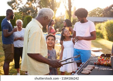 Grandad and grandson talk by the grill at a family barbecue - Powered by Shutterstock