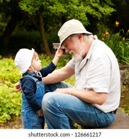 Grandchild And Grandfather Having Fun Outdoors.