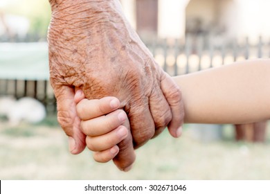 Grandchild holding grandparent for the hand,selective focus 