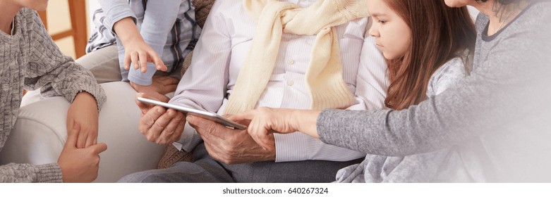 Grandchildren And Grandparents Watching Photos On Tablet Together