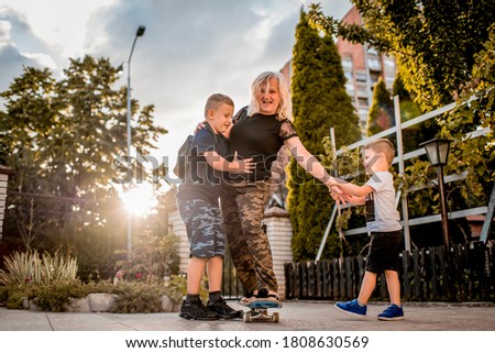 Grandchildren helping his grandmother to learn how to ride skateboard