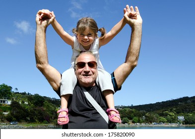 Granddad Carry His Grandchild (granddaughter Girl Age 5) On His Shoulder On Summer Travel Holiday Vacation. Real People. Copy Space