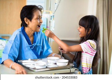 Granddaughter is feeding her grandmother with vegetable in the hospital