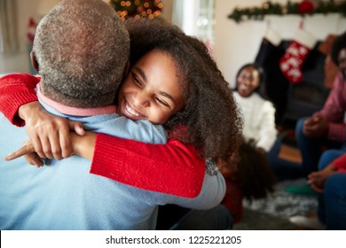 Granddaughter Giving Grandfather Hug As Multi Generation Family Celebrate Christmas At Home