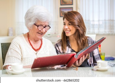 Granddaughter with her grandmother looking at photo album.