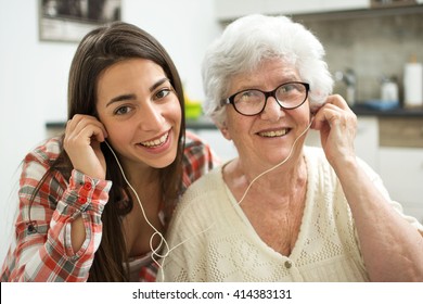 Granddaughter listening music with her grandmother at home.