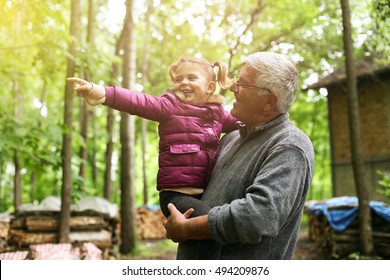 Granddaughter pointing with finger her grandfather something in forest.