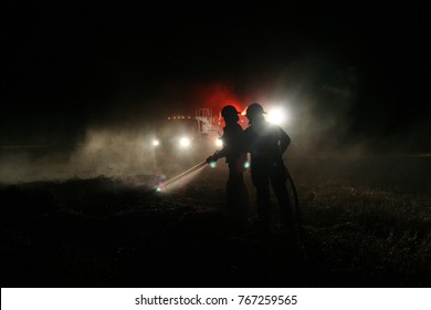 Grande Prairie, Canada - November 4, 2007: Firefighters Are Silhouetted By The Lights Of Their Firetruck As They Put Out A Fire At Night.