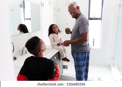 Grandfather In Bathroom Wearing Pajamas Brushing Teeth With Grandchildren - Powered by Shutterstock