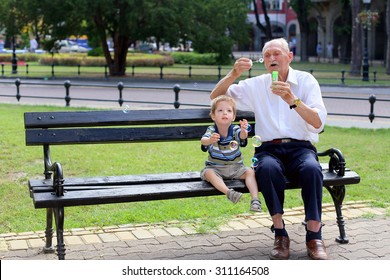 grandfather blowing soap bubbles to grandchild