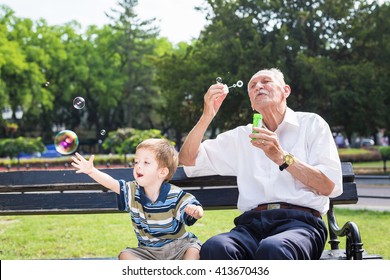 grandfather blowing soap bubbles to grandchild