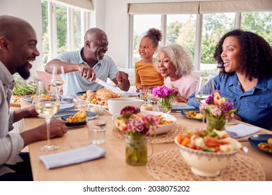 Grandfather Carving As Multi Generation Family Sit Around Table At Home And Enjoy Eating Meal - Powered by Shutterstock