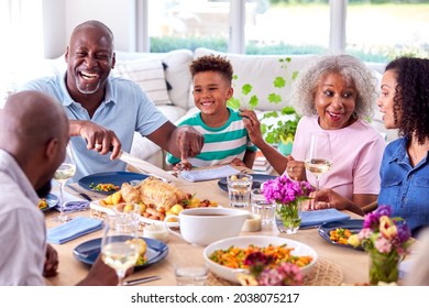 Grandfather Carving As Multi Generation Family Sit Around Table At Home And Enjoy Eating Meal - Powered by Shutterstock