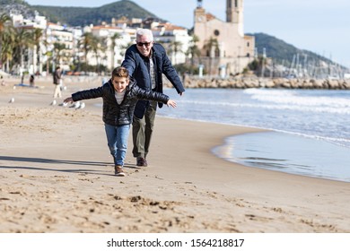 Grandfather Chasing Her Grandson On The Beach