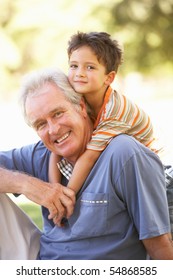 Grandfather Giving Grandson Ride On Back In Park