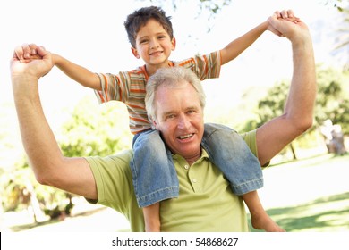 Grandfather Giving Grandson Ride On Back In Park