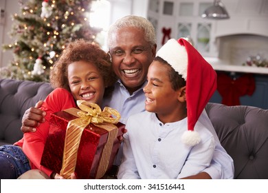 Grandfather With Grandchildren Opening Christmas Gifts