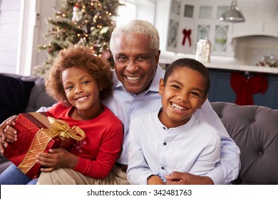 Grandfather With Grandchildren Opening Christmas Gifts