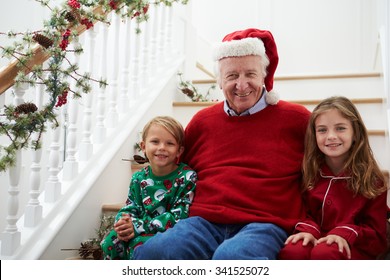 Grandfather With Grandchildren Sits On Stairs At Christmas