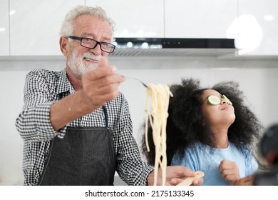 Grandfather And Granddaughter Making Food. Portrait Of Nice Cheerful Kind Grey-haired Grandparent Teaching Grandchild Cooking Homemade. At Modern Light White Interior Kitchen House. Spaghetti.