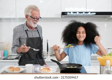 Grandfather And Granddaughter Making Food. Portrait Of Nice Cheerful Kind Grey-haired Grandparent Teaching Grandchild Cooking Homemade. At Modern Light White Interior Kitchen House. Spaghetti.