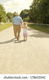 Grandfather with granddaughter walk along the road,
