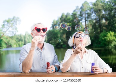 Grandfather and grandmother. Grandfather and grandmother feeling entertained while using soap bubbles of their grandchildren