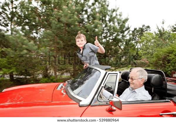 Grandfather and\
grandson driving in vintage\
car