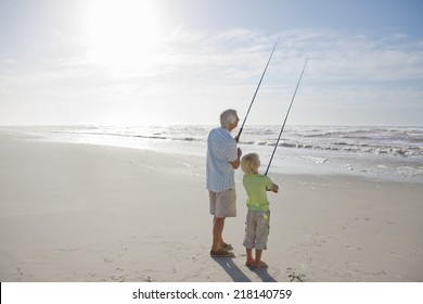 Grandfather And Grandson Fishing On Sunny Beach