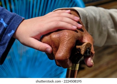 Grandfather And Grandson Holding Hands. Mixed Race Family. Dark Skin Toned Grandfather With Light Skin Toned Grandchild. Grandchild Holding Grandparent's Hand. Grandfather Leaning On A Walking Stick.