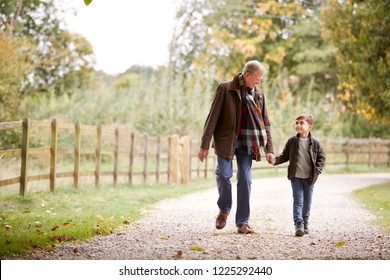 Grandfather With Grandson On Autumn Walk In Countryside Together