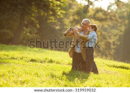 Grandfather and grandson photographing nature in park