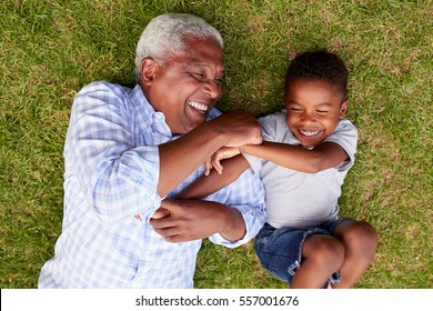 Grandfather and grandson play lying on grass, aerial view