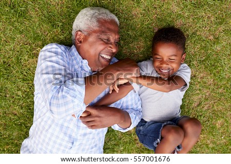 Grandfather and grandson play lying on grass, aerial view
