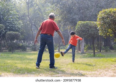 Grandfather and grandson playing with ball at park
