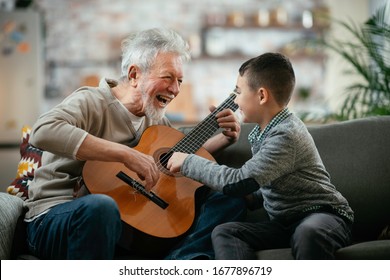 Grandfather and grandson playing guitar. Grandfather and grandson enyoing at home. 