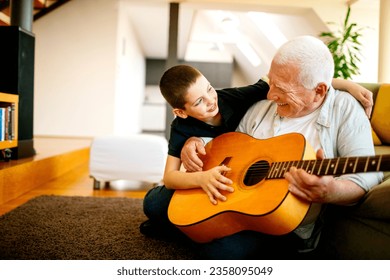 Grandfather and grandson playing the guitar in the living room at home - Powered by Shutterstock