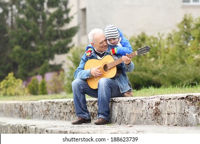 Grandfather and grandson playing guitar outdoors - Powered by Shutterstock