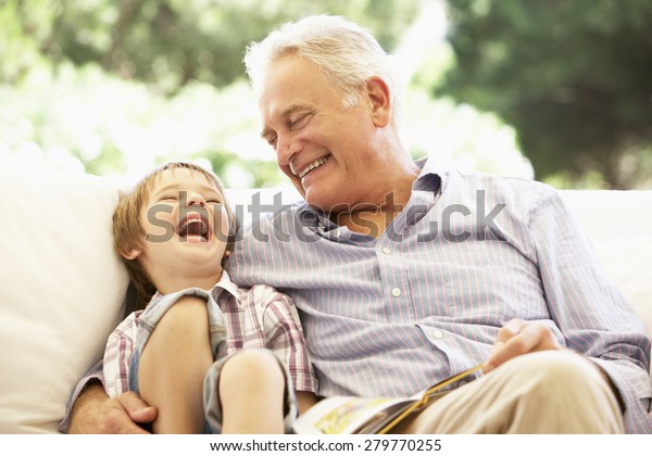 Grandfather With\
Grandson Reading Together On\
Sofa