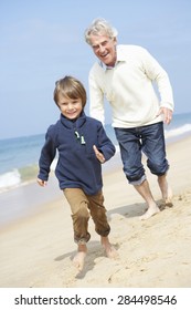 Grandfather And Grandson Running Along Beach