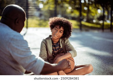 Grandfather and grandson sitting on basketball court bonding after game - Powered by Shutterstock