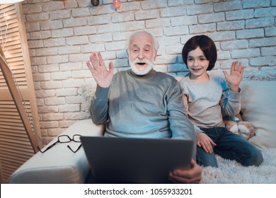 Grandfather and grandson are talking on skype with family sitting on couch at night at home. - Powered by Shutterstock