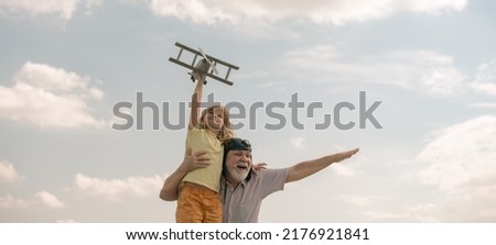 Grandfather and grandson with toy plane over blue sky and clouds background. Two men generation grandfather and grandson playing outdoors.
