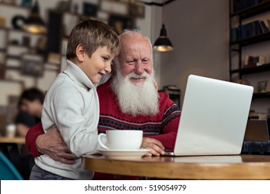 Grandfather and grandson using laptop together - Powered by Shutterstock