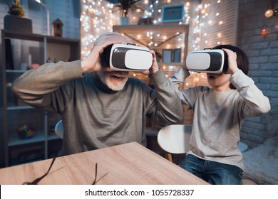 Grandfather and grandson are using virtual reality at table at night at home. - Powered by Shutterstock