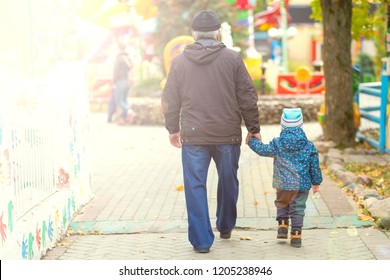 grandfather and grandson walk together in the park