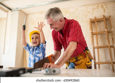 Grandfather And Grandson Working With Wood In A Garage